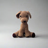 Brown hand crocheted dog sitting with the hind paws spread out and the front paws placed in front with the tail upright