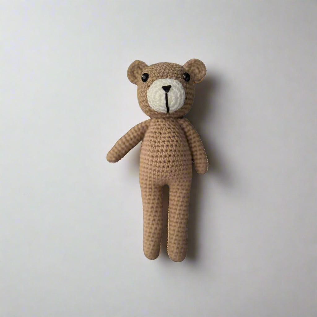 Crochet plush teddy bear placed against a white background