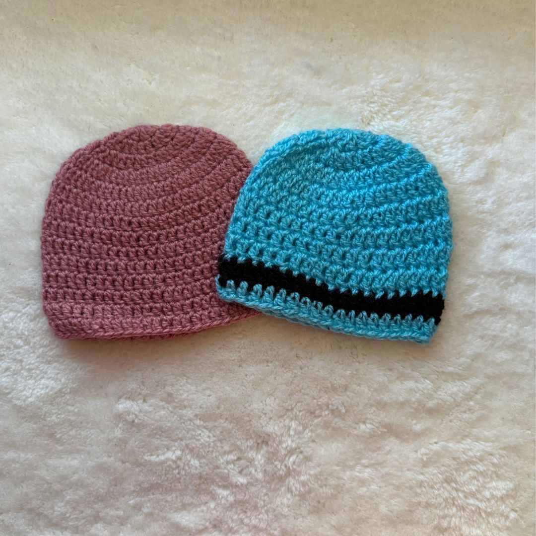 Pink beaning and Blue beanie placed on a s oft white fabric