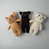 Crochet plush cats in brown, black and white placed against a white background