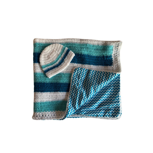 Blue and white striped baby blanket lined with a wavy liner with a baby beanie paced on the baby blanket, against a white background