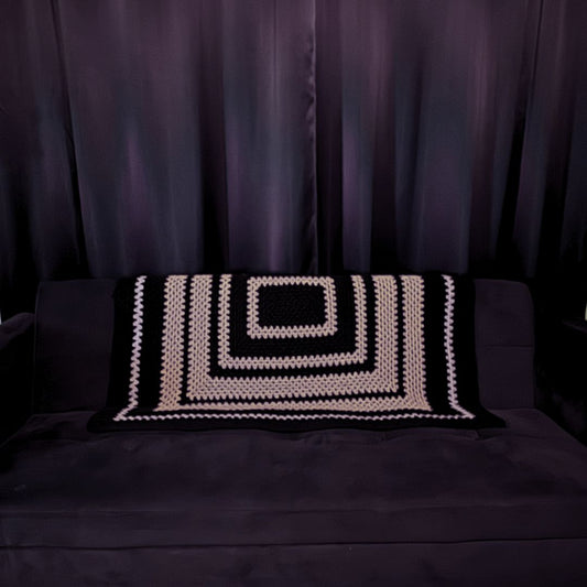 granny square black and grey granny patterned sofa throw on a black sofa with black curtains in the background