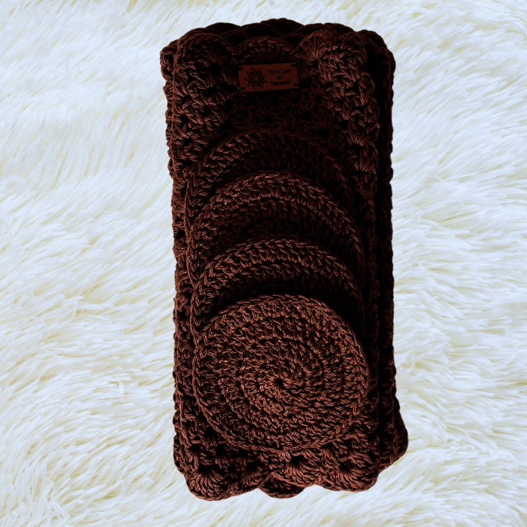 Brown hand crocheted place mats with coasters on top placed on a soft white fabric