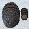Grey hand crocheted place mats with coasters on top placed on a soft white fabric