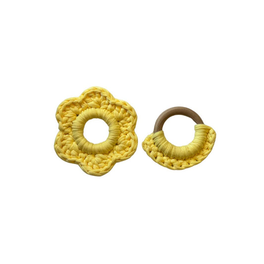 Yellow flower shaped teether, wooden teether ring with yellow yarn placed against a white background