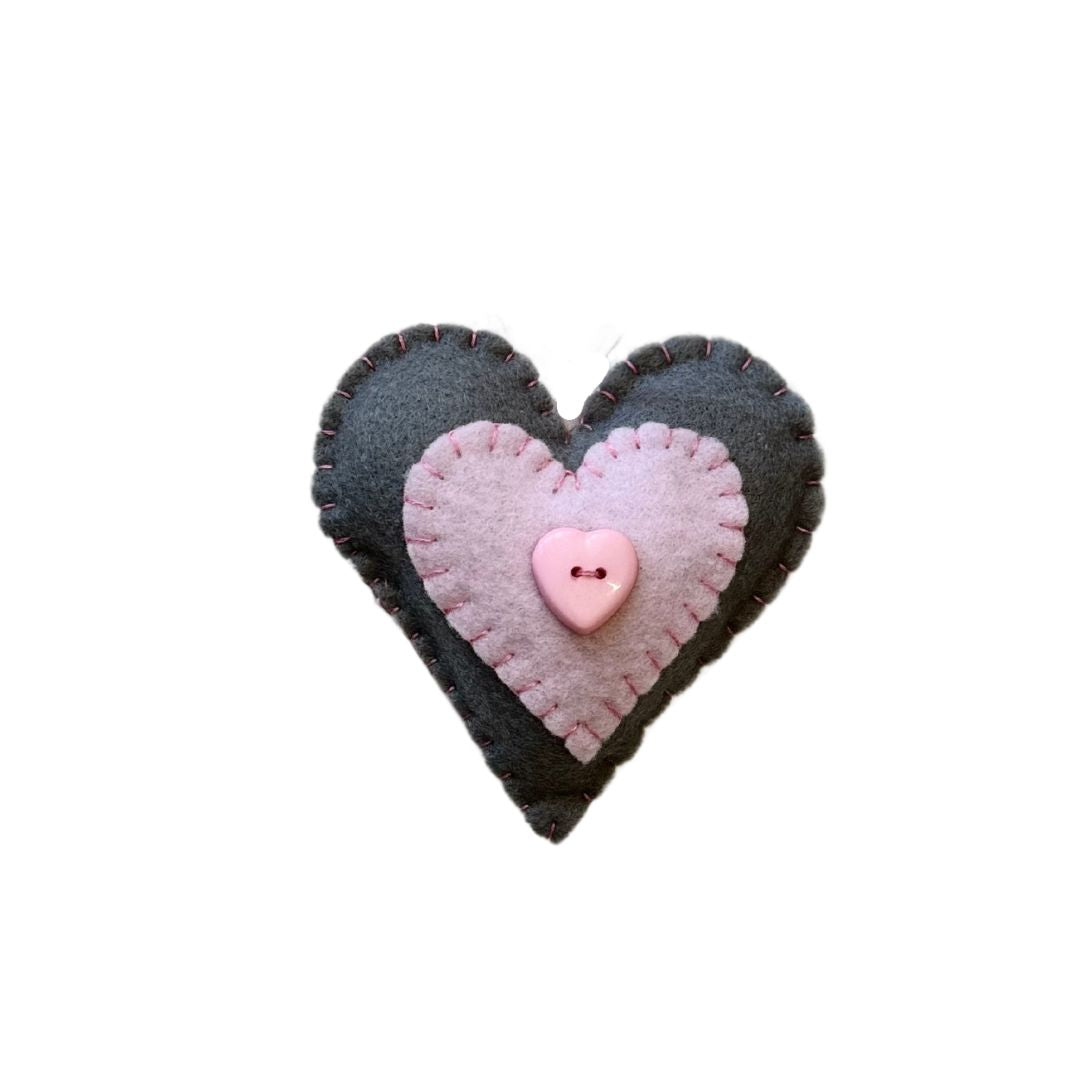 Grey and pink heart shaped felt ornament placed agains a white background