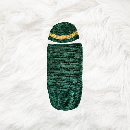 Green Crochet baby cocoon with a baby beanie placed on a white fur fabric