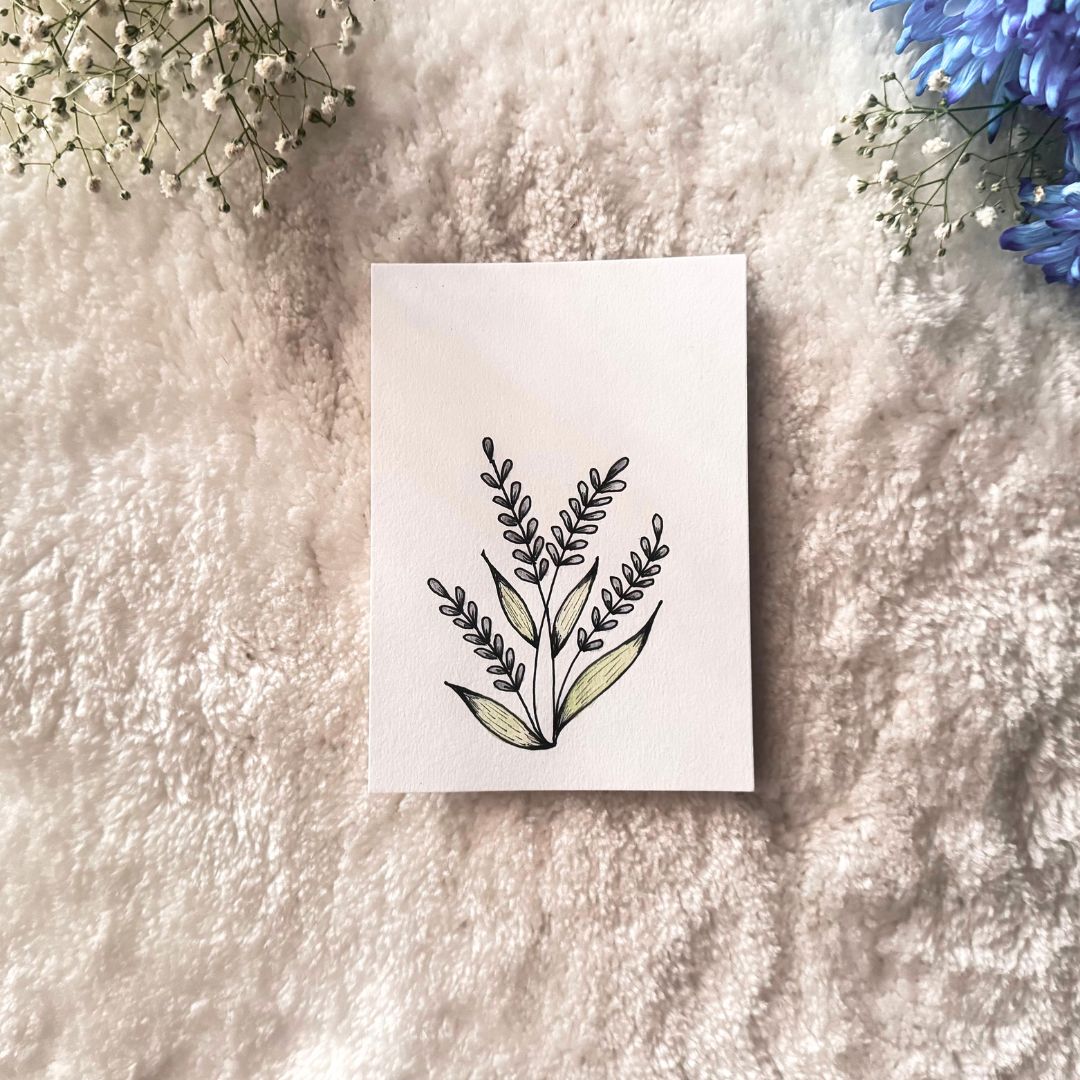 Light purple colored petals on stalks with green leaves painted on a white card placed on a textures surfaces with decorative flowers in the background