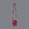 Maroon macrame small bag with a long handle placed against a grey background
