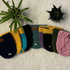Pot cozy cover collage placed on soft white fabric with small pot plants in the background