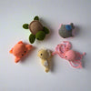 Crochet plushie set of a orange crab, yellow seahorse, grey whale, green turtle and pink octopus placed on a w white table