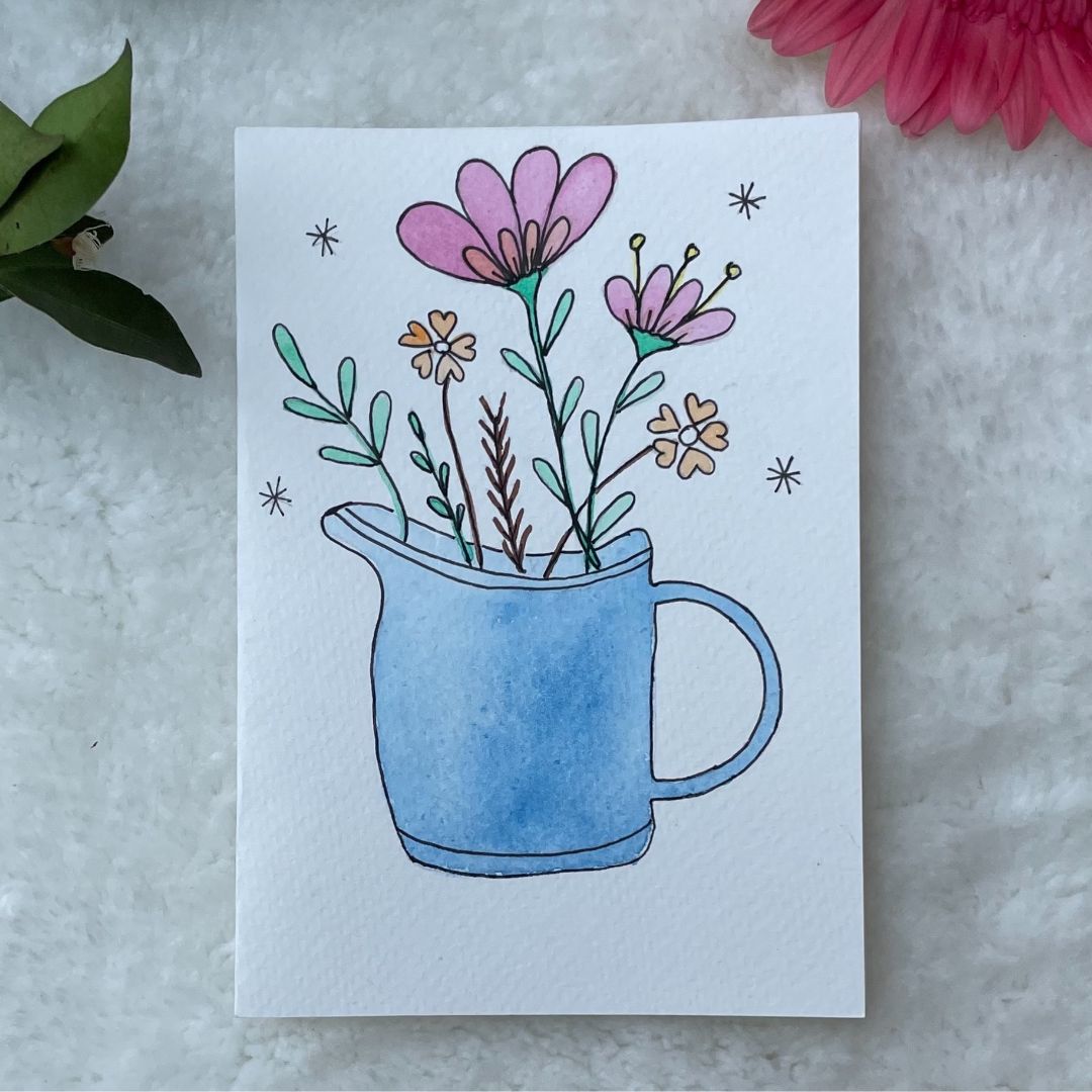 Blue watering can filed with flowers hand painted on a greeting card