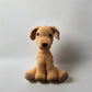 Beige hand crocheted dog sitting with the hind paws spread out and the front paws placed in front with the tail upright 