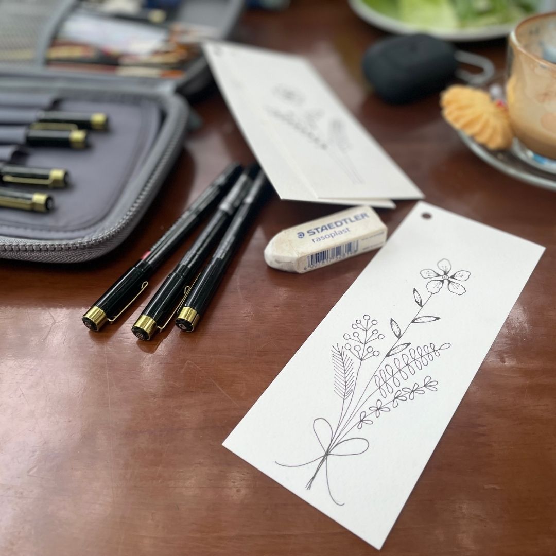 Pens, eraser, and black and white bookmark on a wooden surface with a blurred background