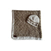 A crochet baby blanket in earth tones with a textured pattern, accompanied by a matching baby beanie hat placed on a whit background 