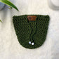 Olive Green hand crocheted pot cozy with a drawstring and a faux leather olive leaf label placed on white fur fabric 