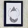 A hand-drawn black and white mandala design on a greeting card with a blank interior, placed on a fluffy white background.