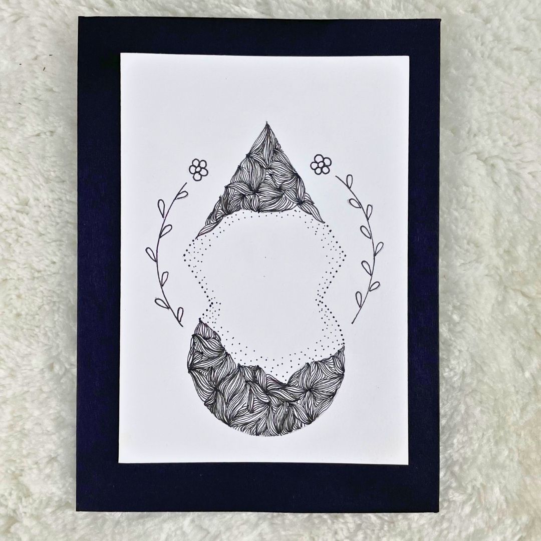 A hand-drawn black and white mandala design on a greeting card with a blank interior, placed on a fluffy white background.