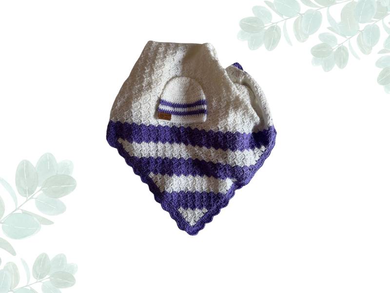 Baby blanket in white with purple stripes with a baby beanie placed on top of it against a white background