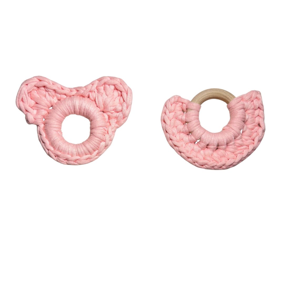 Two pink crochet wooden teethers on a white background