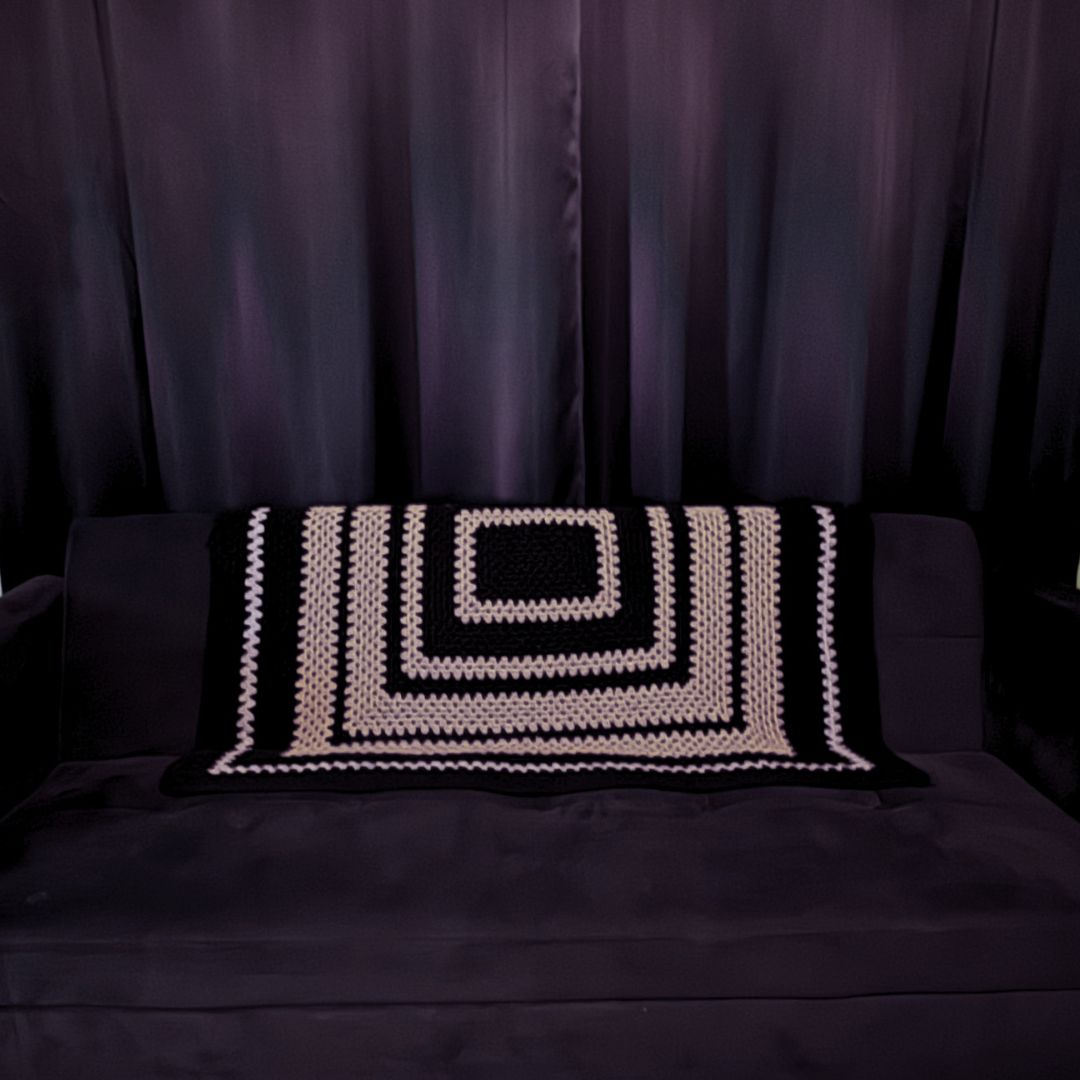 granny square black and grey granny patterned sofa throw on a black sofa with black curtains in the background 