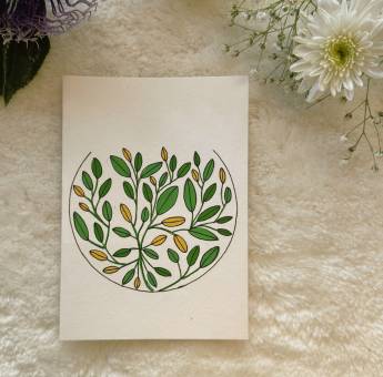 Abstract mandala filled with yellow and green leaves painted on a card, place on a white background with fresh flowers 