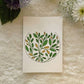 Abstract mandala filled with yellow and green leaves painted on a card, place on a white background with fresh flowers 