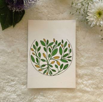 Abstract mandala filled with yellow and green leaves painted on a card, place on a white background with fresh flowers 