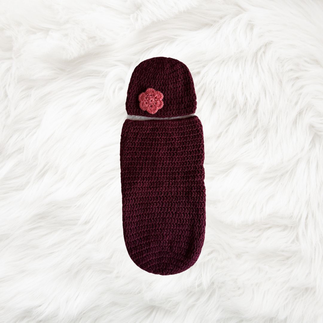 Maroon Crochet baby cocoon with a baby beanie placed on a white fur fabric