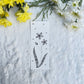 Floral sketch in black and white on a bookmark placed on fur fabric with fresh flowers in the background 