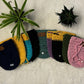 Pot cozy cover collage placed on soft white fabric with small pot plants in the background
