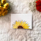 Card with a sunflower design a white card placed on a textured surface with decorative flowers around